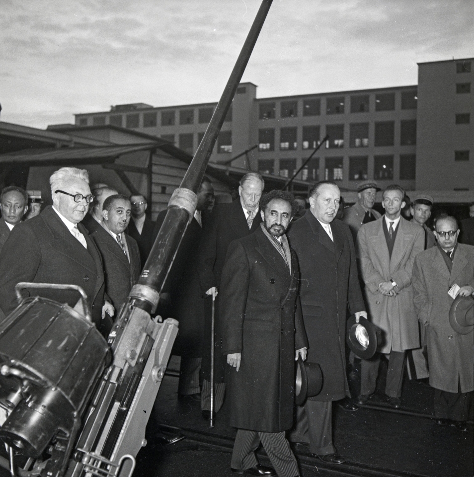 Emil Georg Bührle (di spalle, con bastone da passeggio) mostra all'imperatore etiope Hailé Selassié (al centro) i suoi cannoni nel novembre 1954 (Björn Erik Lindros, ETH-Bildarchiv).